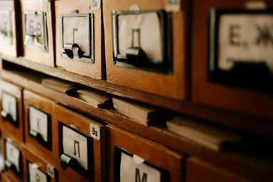 Holzregal mit beschrifteten Schubladen für Karteikarten